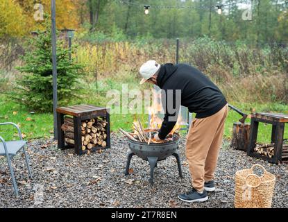 A man lights a barbecue in nature near the house Stock Photo