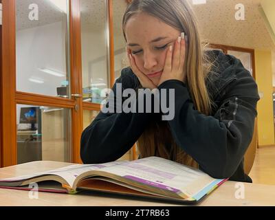 Schülerin schaut verzeifelt in ein Schulbuch *** Pupil looks forlornly into a schoolbook Copyright: xmix1x Credit: Imago/Alamy Live News Stock Photo