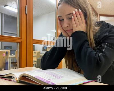Schülerin schaut verzeifelt in ein Schulbuch *** Pupil looks forlornly into a schoolbook Copyright: xmix1x Credit: Imago/Alamy Live News Stock Photo