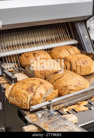 Sourdough bread slicing in industrial bread slicing machine in bread factory Stock Photo