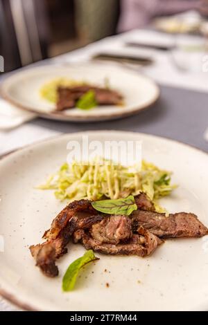 Wagyu entrecote beef steak slices with fresh lettuce on a white plate Stock Photo