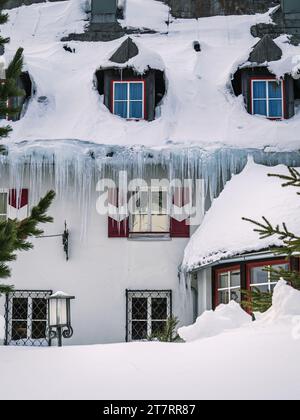 Large icicles and snow cover on a hotel building during winter in a ski resort, Carinthia, Austria Stock Photo