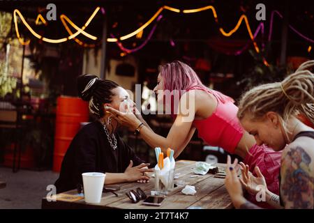 Women friends are having fun, smearing each other glitter with stars. Stock Photo