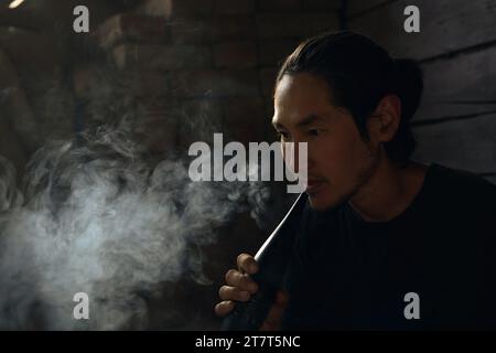 A man smokes a hookah at home in the yard Stock Photo