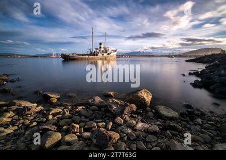 Rocks and a completely calm sea in the foreground with a ship ag Stock Photo