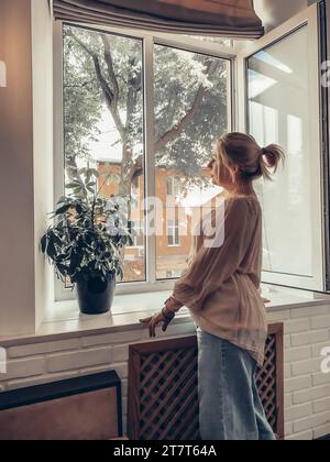 A woman looks out the window Stock Photo