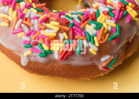 Vanilla Frosted Rainbow Sprinkle Donut on a Yellow Background Stock Photo