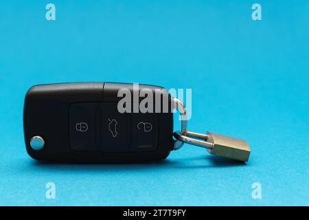 Padlock attached to a black car keys on blue background Stock Photo