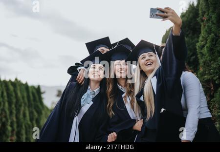 Group of students taking the last selfie after they graduated from college on a beautiful day in the park. Stock Photo