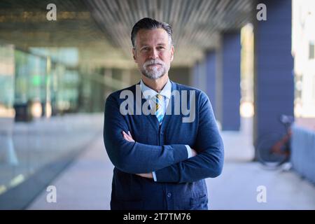 Caucasian adult portrait serious expression business man with gray hair and crossed arms. Copy space Stock Photo