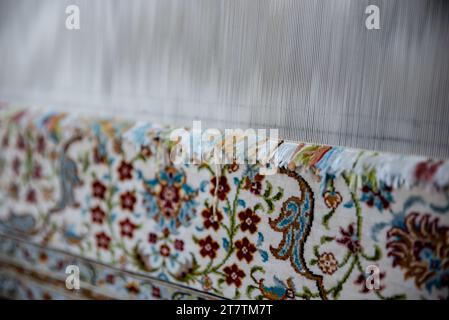 weaving carpet ,a diligent woman makes a traditional carpet by hand , Loom for hand weaving carpet with woman,extract. Stock Photo
