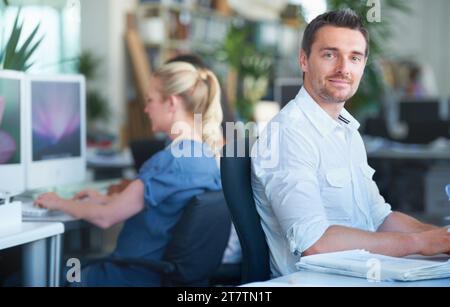 Smile, happy and businessman working in the office on a creative project with documents. Professional, paperwork and young male designer planning with Stock Photo