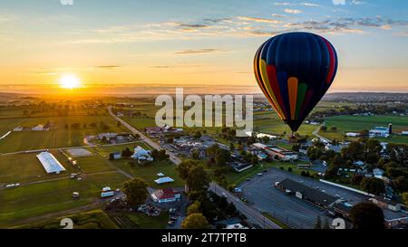 An Aerial View of a Multi-Colored Hot Air Balloon, Floating Over Pennsylvania Farmlands at Sunrise, on a Summer Day Stock Photo