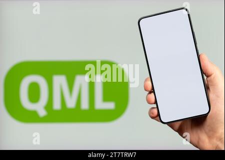 New York, USA - November 15, 2023: Create mobile app on QML platform background with smartphone clean screen in hand Stock Photo