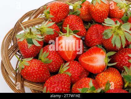 Ripe strawberries in a wicker tray on a white background, close up. Stock Photo