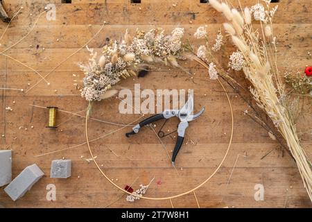 Overhead view of a florist's workspace with the beginnings of a wreath, tools, and materials Stock Photo