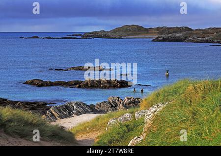 A view of Bosta Beach at high water with two swimmers and the Tide and Time Bell installation on Bernera, Isle of Lewis, Outer Hebrides, Scotland. Stock Photo