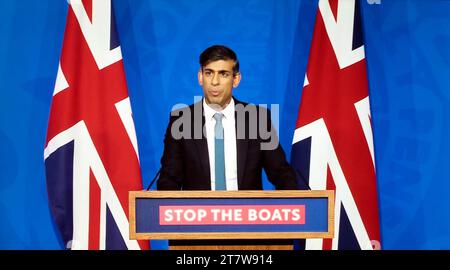 Prime Minister Rishi Sunak standing at podium with Stop the Boats sign  flanked by Union Jack flags speaking 15 November 2023 London UK Stock Photo