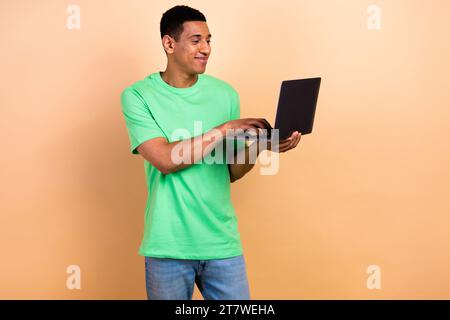 Photo portrait of nice young male working coding laptop wear trendy green outfit isolated on beige color background Stock Photo