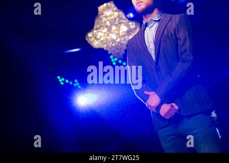 Male model presents new creation on the runway from autumn/winter collection during fashion week show. Blue light. Stock Photo