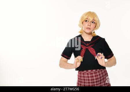 dreamy woman in blonde wig touching red neckerchief and looking away on white, anime style concept Stock Photo