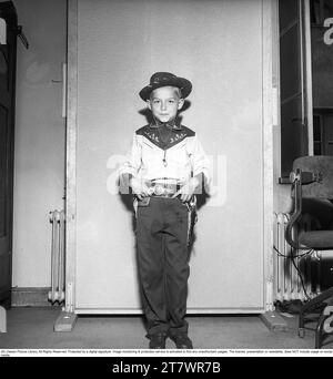 Boy in the 1950s. A boy is dressed in cowboy clothes, shirt, gun holster and cowboy hat and holds two toy revolvers. 1950. Kristoffersson ref AZ47-9 Stock Photo