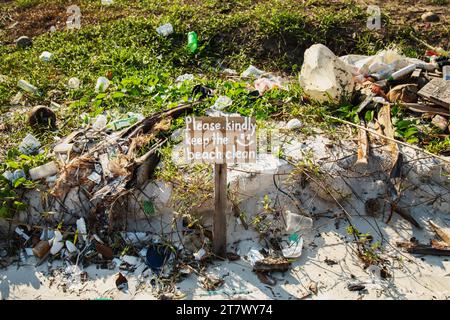 Sign saying ''Please kindly keep the beach clean'' and pile of different plastic and waste Stock Photo