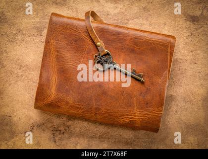 retro leather-bound journal with a decorative key on a handmade bark paper, journaling concept Stock Photo