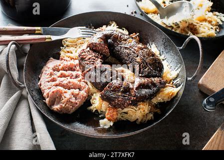 Bloody sausage morcilla, stewed sauerkraut and mashed potato with beans close up. Traditional Slovenian dish with roasted bloody sausage Stock Photo