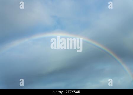 Real photo of a rainbow in the sky with clouds and blue sky Stock Photo
