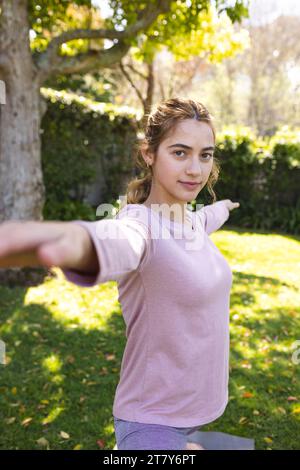 Portrait of happy biracial woman practicing yoga standing stretching in sunny garden, copy space Stock Photo