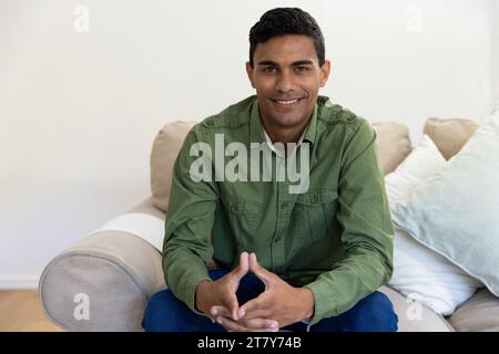 Portrait of happy biracial man sitting on sofa at home Stock Photo