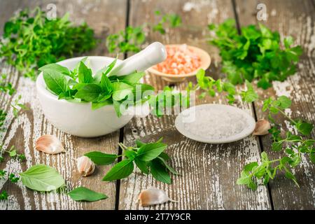 Thai basil and spicy herbs with Himalayan salt for healthy cooking on wooden table Stock Photo