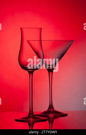Empty glass wine glass on a red background. Wine glass for a drink on a red background. Dark silhouette of a glass. Stock Photo