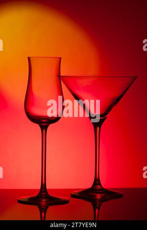 Empty glass wine glass on a red background. Wine glass for a drink on a red background. Dark silhouette of a glass. Stock Photo