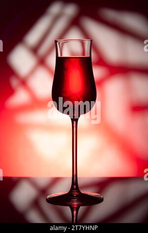 Glass of wine on a red background. Glass of wine with drink on a red abstract background. Stock Photo