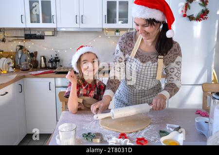 Mom and daughter in the white kitchen are preparing cookies for Christmas and new year. Family day, preparation for the holiday, learn to cook delicio Stock Photo