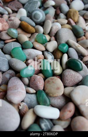 Green quartz stones are scattered on small pebbles with shells vertical stock photo for backgrounds Stock Photo