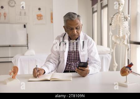 Serious elder Indian doctor man giving medical consultation on Internet Stock Photo