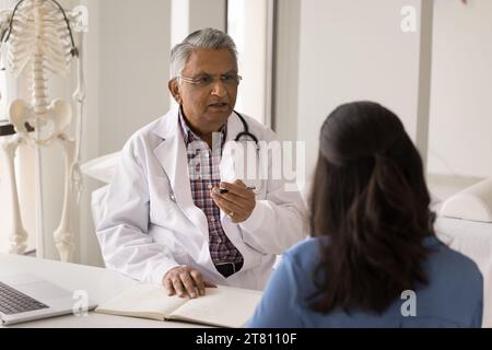 Serious senior Indian doctor man giving consultation to patient Stock Photo