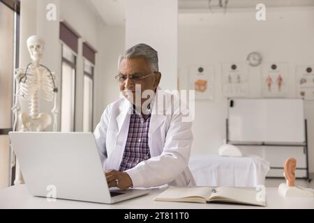 Senior Indian medical practitioner man working in hospital office Stock Photo