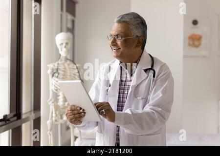 Happy mature Indian practitioner man using medical app Stock Photo