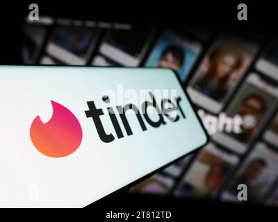 Mobile phone with logo of American online dating app Tinder in front of business website. Focus on left of phone display. Stock Photo