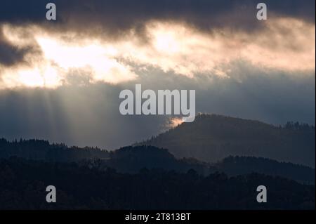 Dramatic evening sky with sun rays and clouds above hills and mountains near to Roznov pod Radhostem, Czech republic. Late Autumn. Stock Photo