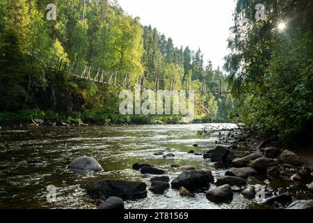 A suspension bridge over a fast flowing river in the forest in northern Finland Stock Photo