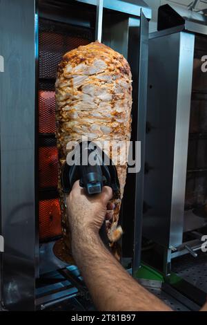 Chef uses slicer to cut kebab roll Stock Photo