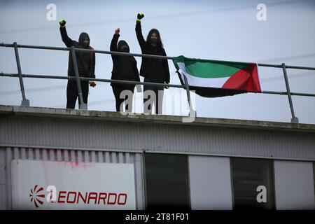 Southampton, Hampshire, UK. 16th Nov, 2023. Activists raise their fists in the air on the roof beside a Palestinian flag and the Leonardo factory sign. Palestine Action occupy the roof of Italian arms industry, giant Leonardo at their factory in Southampton. Leonardo supply Israel with fighter jets and weaponry that are currently being used in Gaza. Palestine Action demands that arms companies providing weapons for Israel should be shut down permanently. They have announced that companies selling weapons to the Israeli Defence Force and their partner companies will be targeted w Stock Photo