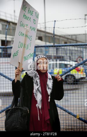 Southampton, Hampshire, UK. 16th Nov, 2023. A supporter of the Palestinian holds a placard at the factory gates. Palestine Action occupy the roof of Italian arms industry, giant Leonardo at their factory in Southampton. Leonardo supply Israel with fighter jets and weaponry that are currently being used in Gaza. Palestine Action demands that arms companies providing weapons for Israel should be shut down permanently. They have announced that companies selling weapons to the Israeli Defence Force and their partner companies will be targeted with direct action. These actions are in Stock Photo