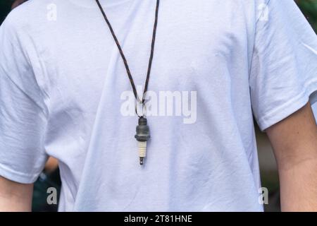 A man in a white T-shirt with a necklace made of spark plugs Stock Photo