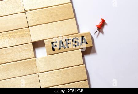 Businessman hand holding wooden cube block with FAFSA business word on table background. Mission, Vision and core values concept Stock Photo